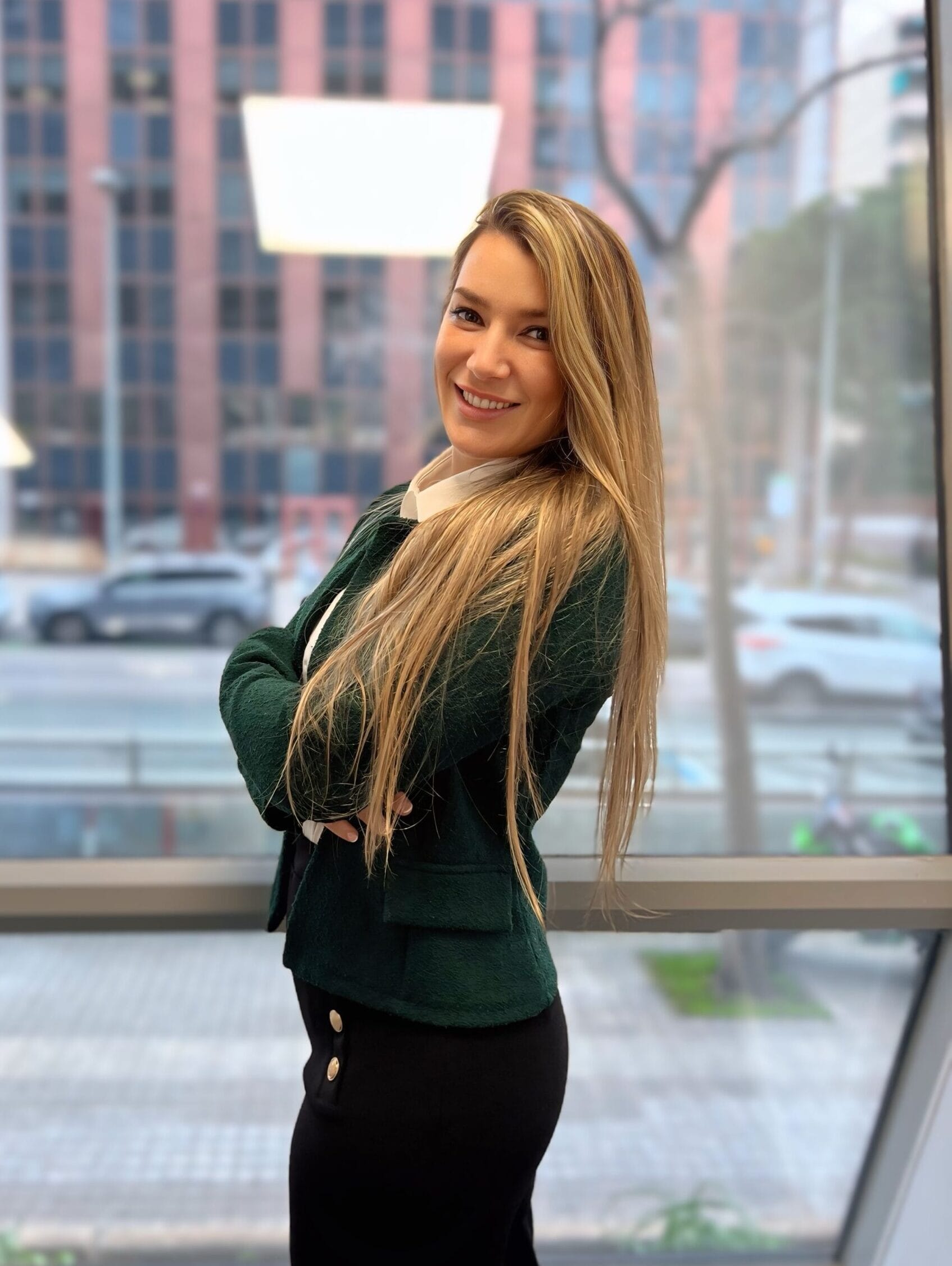 Aroa, asesora financiera, de pie con los brazos cruzados en su oficina, mostrando una postura profesional