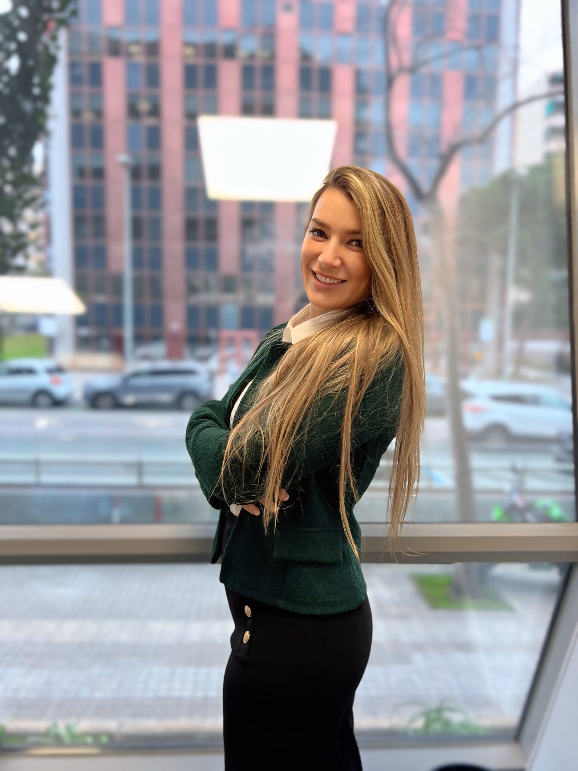 Aroa, asesora financiera, de pie con los brazos cruzados en su oficina, mostrando una postura profesional